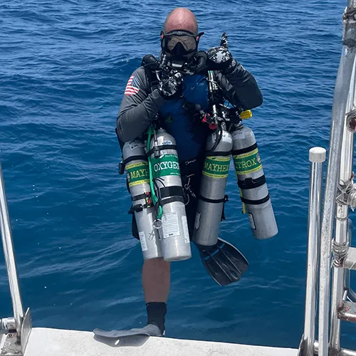 Dan Siegel stepping off the boat rigged with bailout and deco cylinders